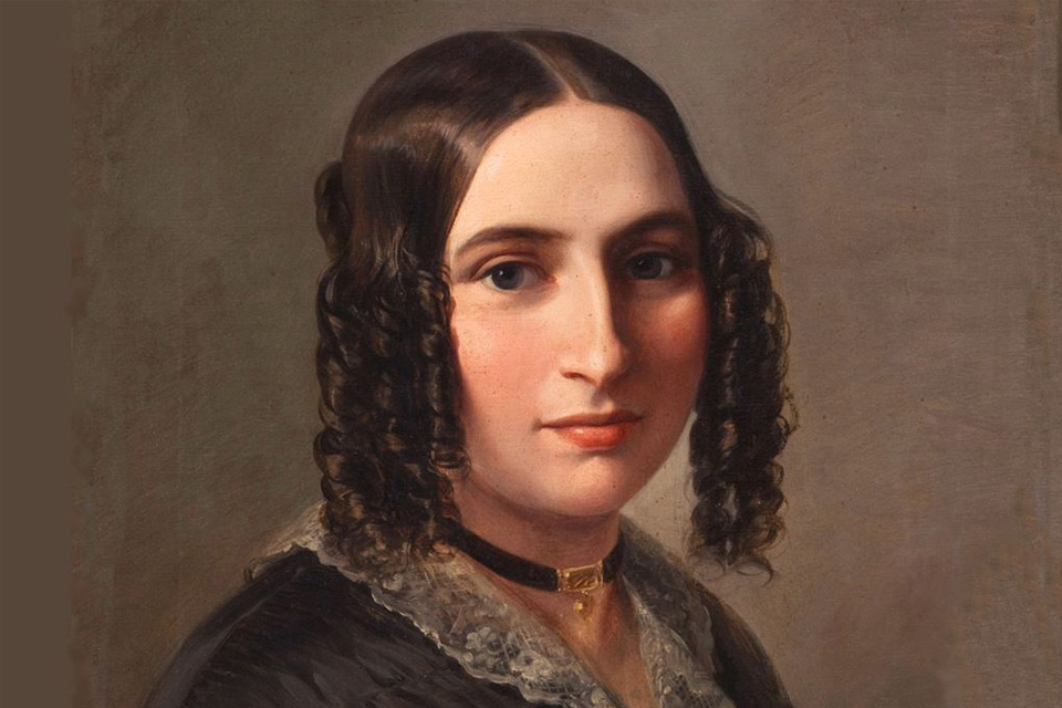 Portrait of a young woman with dark curly hair looking directly towards the viewer