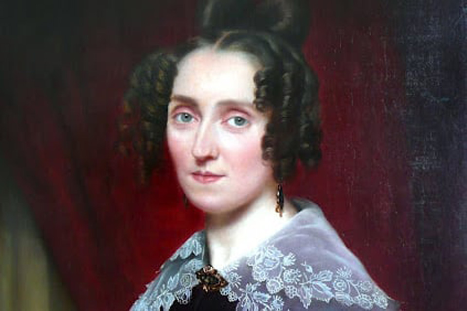 A portrait of a pale white young woman with curly brown hair wearing a lace shawl and looking towards the viewer