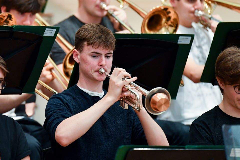 A young man plays the trumpet in an orchestra