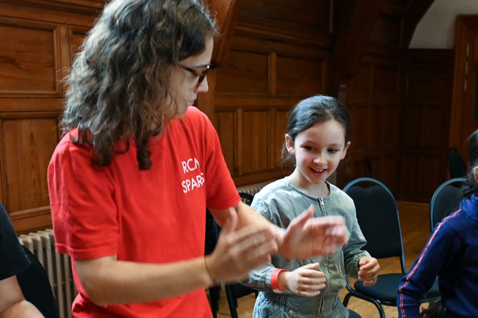 A young girl smiles and claps with a young woman