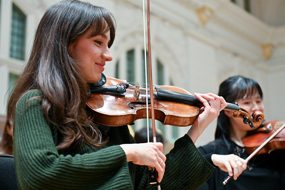 Two violinists perform on stage smiling