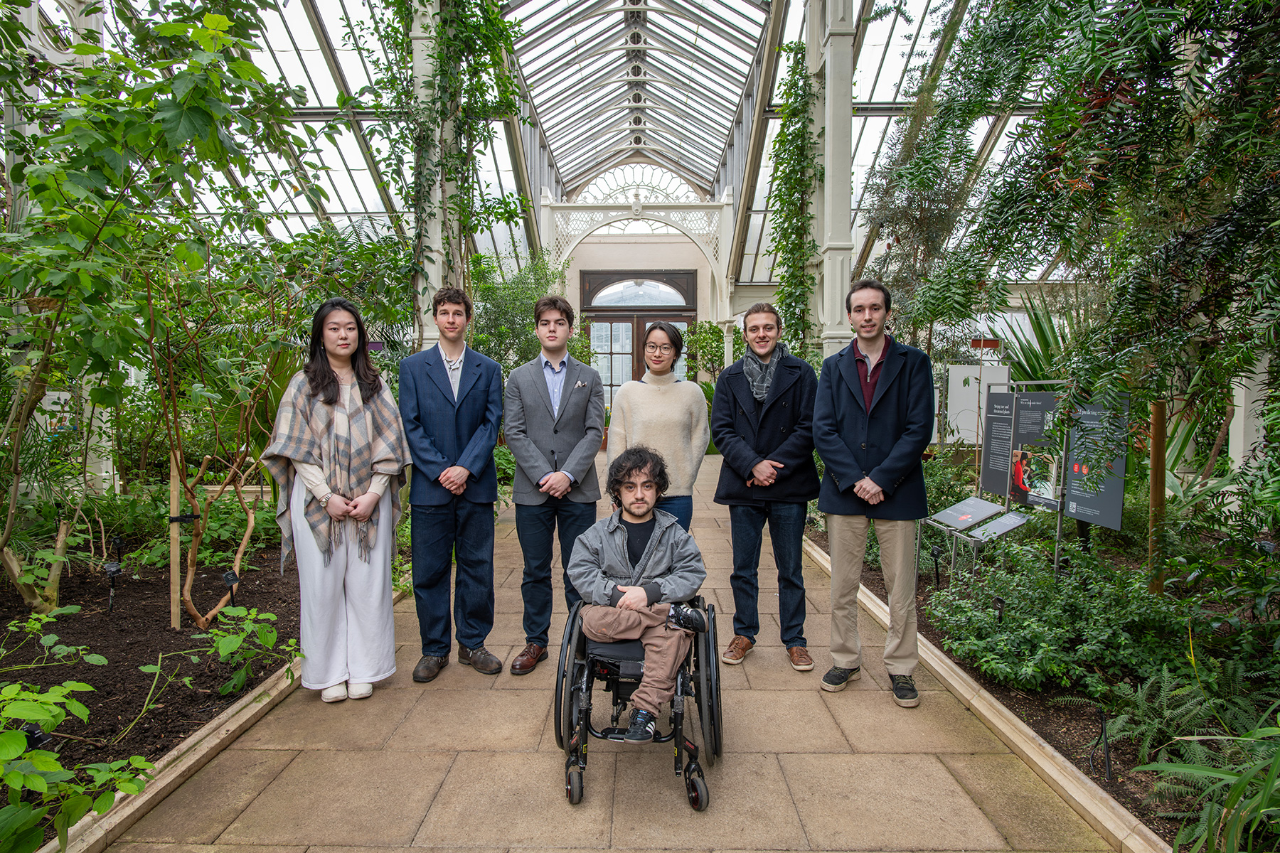 A group of students standing in a walkway in a greenhouse.