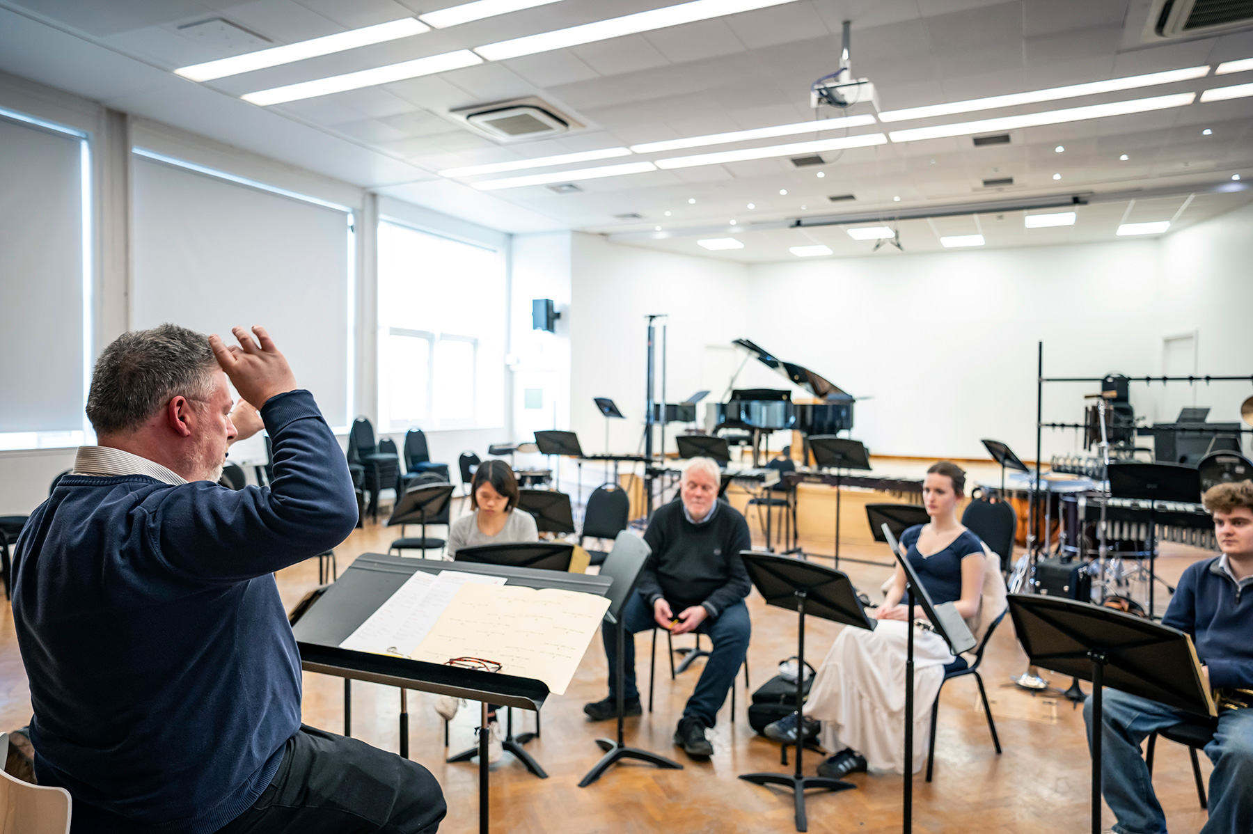 A male teacher leading students in an open rehearsal.