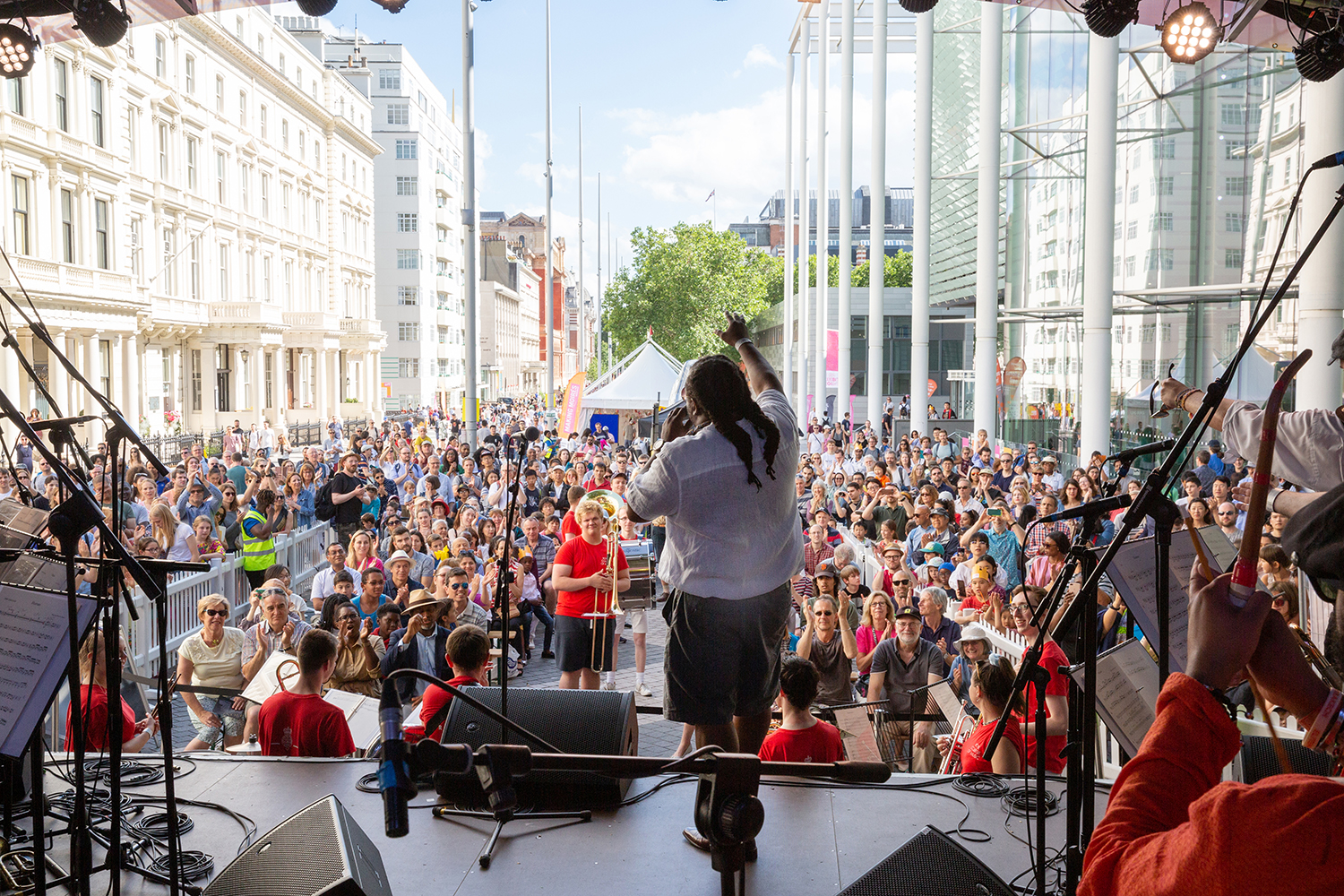 Someone performing on stage to a crowd in the sun on Exhibition Road