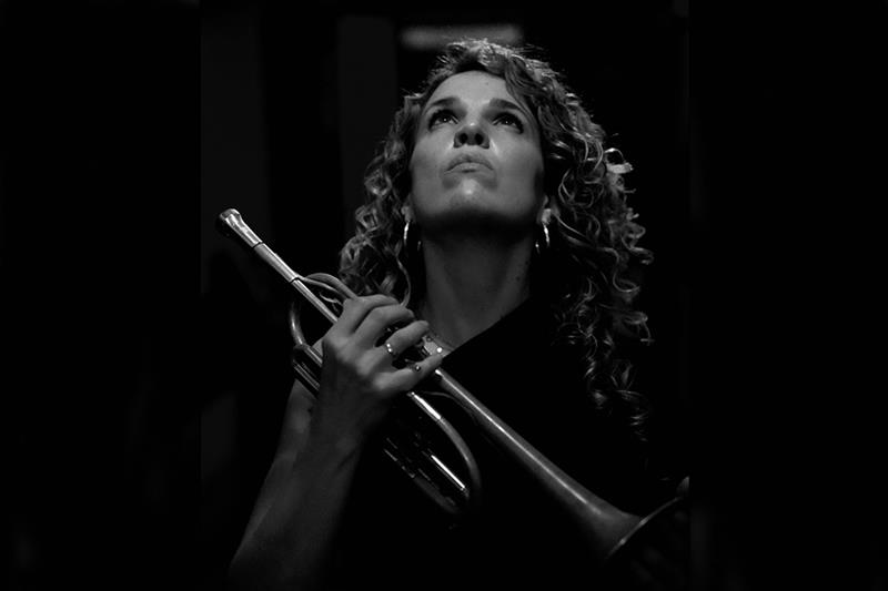 Black and white photo of Mireia Farrés holding a trumpet and looking upwards