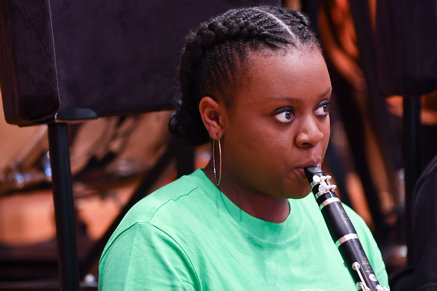 A clarinet player wearing a light green t-shirt performs on her instrument