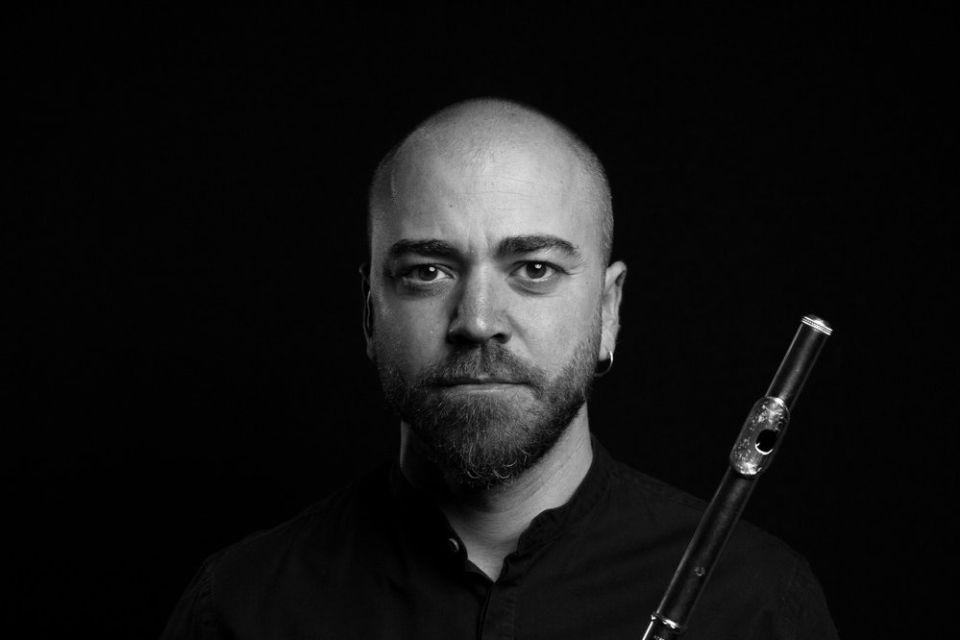A black and white photo of André Cebrián holding his flute