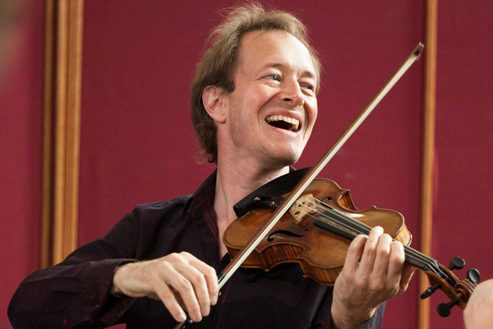 Anthony Marwood plays his violin and looks over his shoulder, laughing