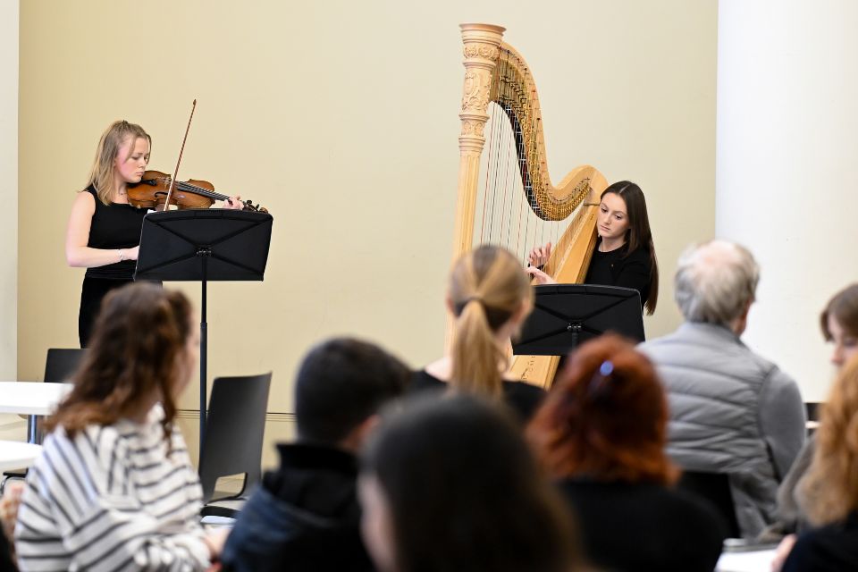 A violinist and harpist perform in a bright cafe