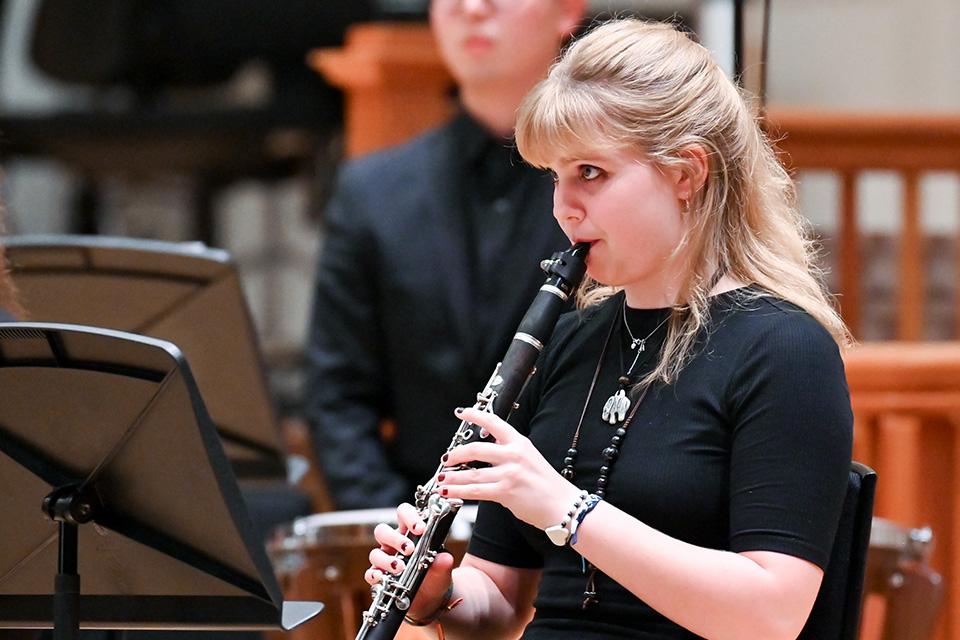 A girl plays the clarinet on stage with a chamber group