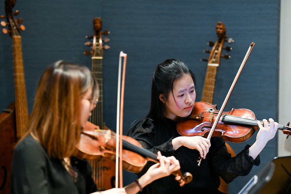 Two violinists play their instruments in the RCM Museum