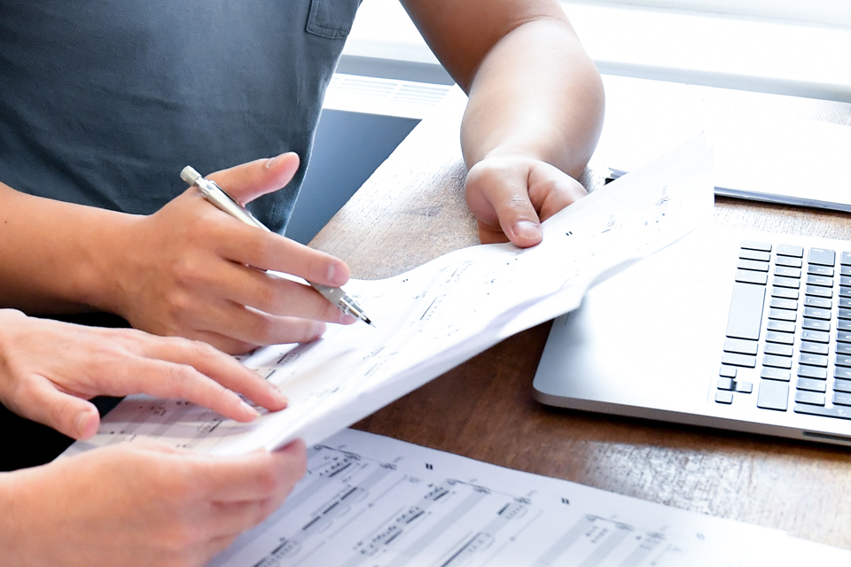 A close up image of two people looking over musical scores