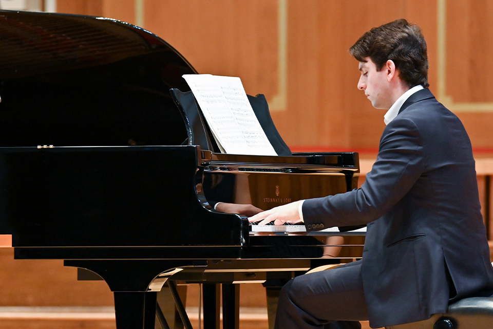 A pianist wears a suit and performs on stage