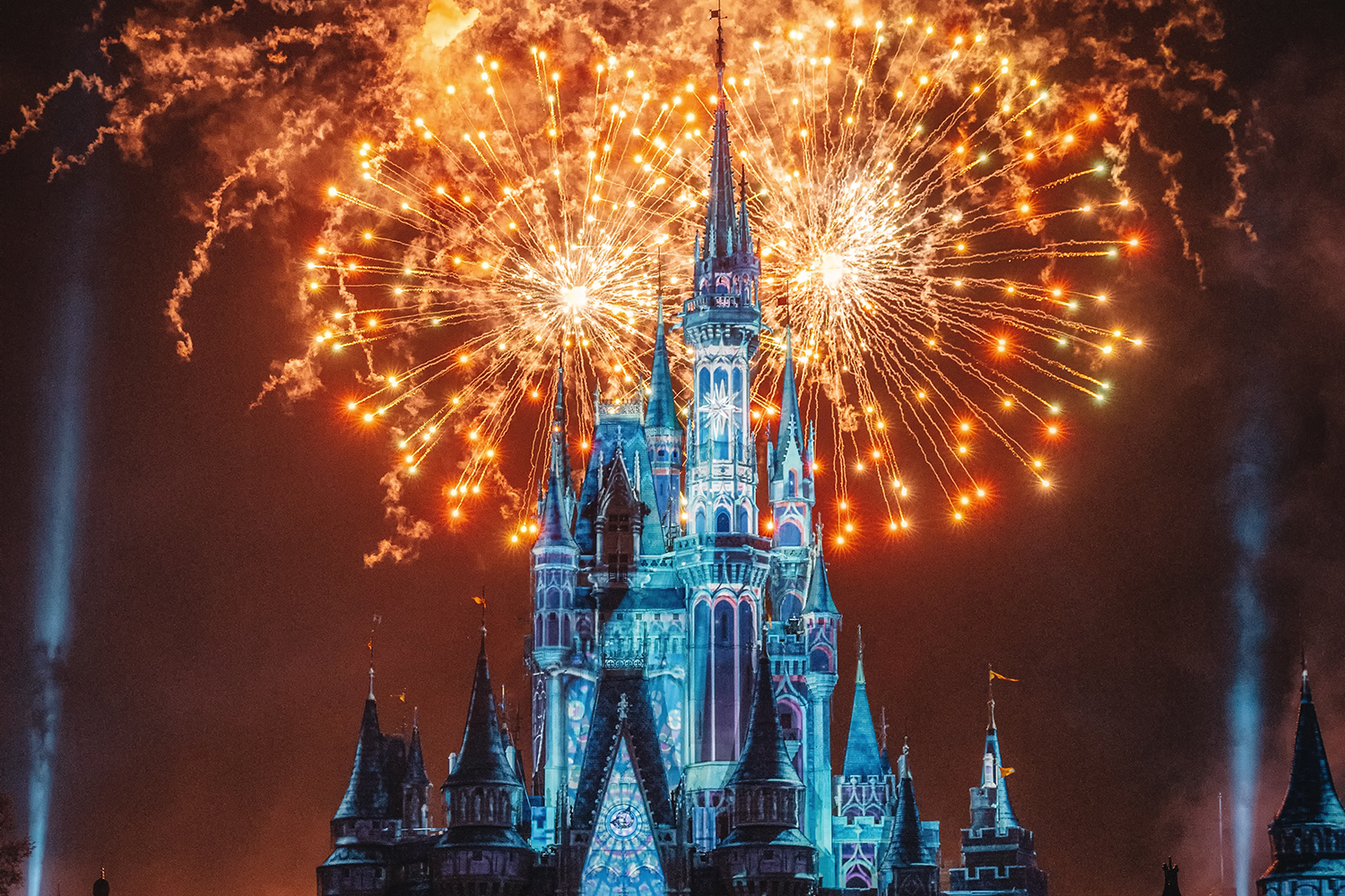 A photograph of the iconic Disney castle against an explosion of orange fireworks