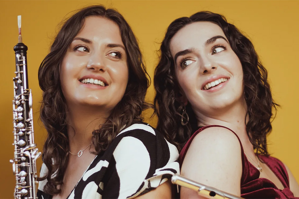 Members of EMPOWER stand back to back and look over their shoulders, smiling, against a yellow background