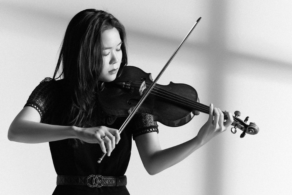 A black and white image of Esther Yoo playing the violin with her eyes closed