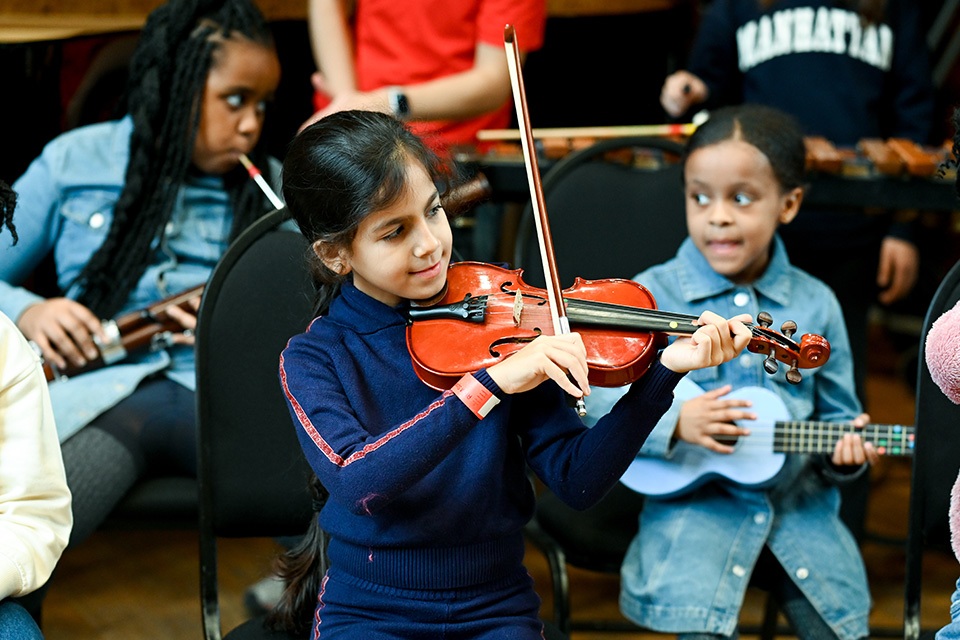 A young girl plays the violin, smiling