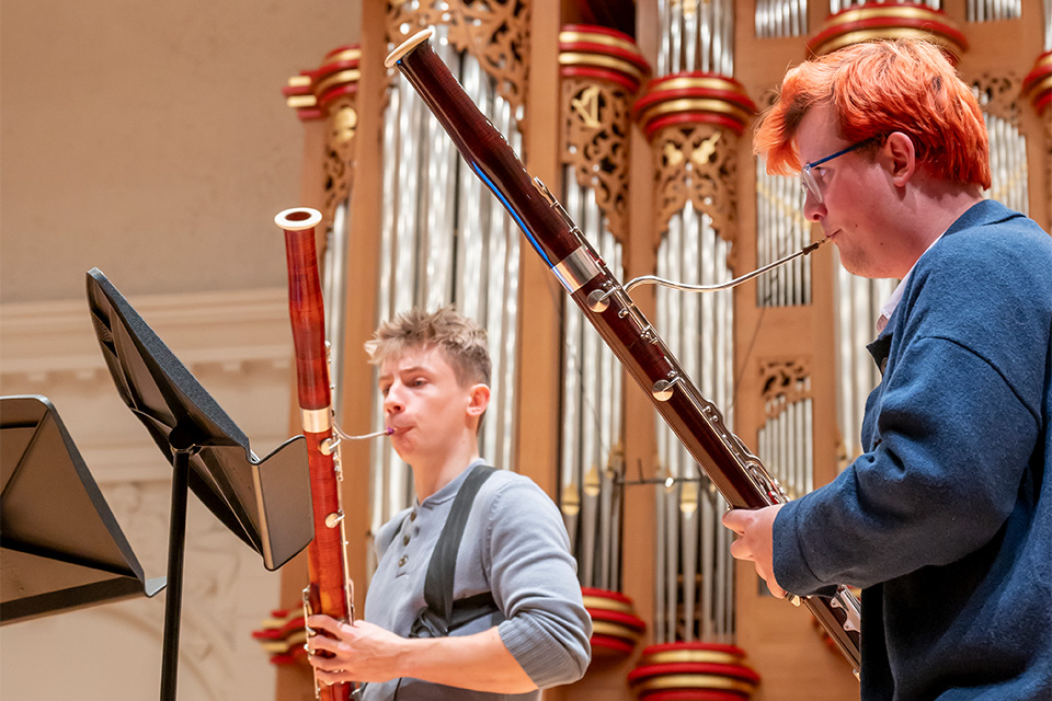 Two bassoonists play their instruments on stage