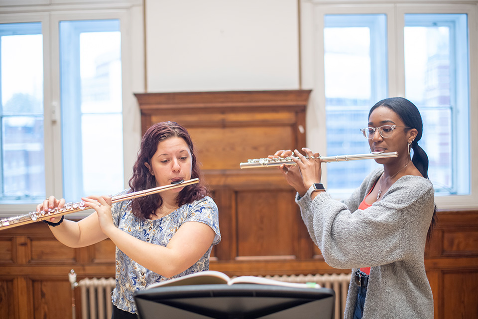 Two flautists play their instruments together