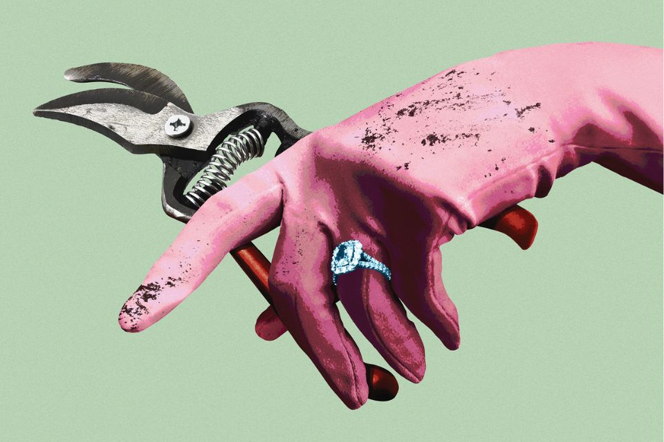 A hand wearing a pink satin glove and wedding ring holds garden shears over a green background