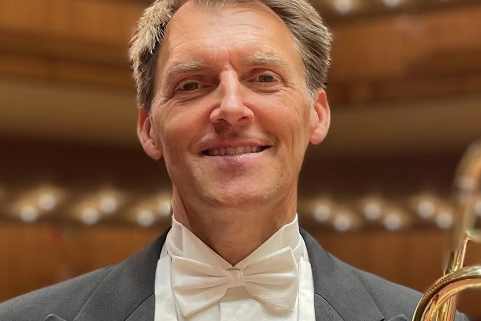 Håkan Björkman wears a white bow tie and tuxedo and stands in a concert hall, smiling