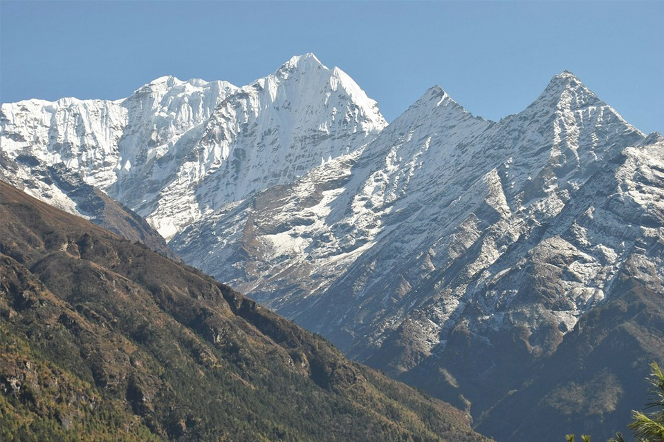 A scenic landscape of the snow-covered Himalayas under a blue sky