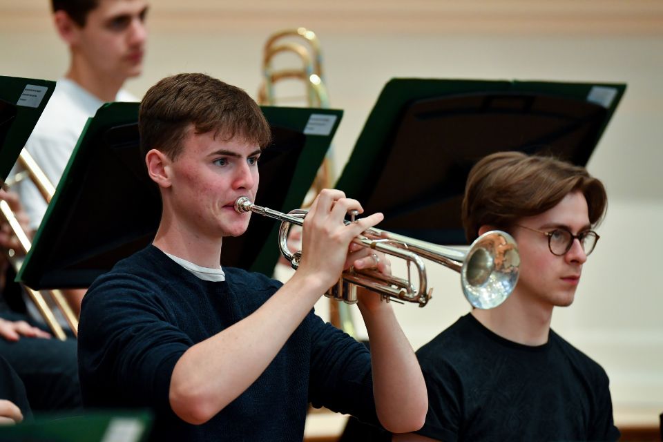 A young man plays the trumpet in an orchestra