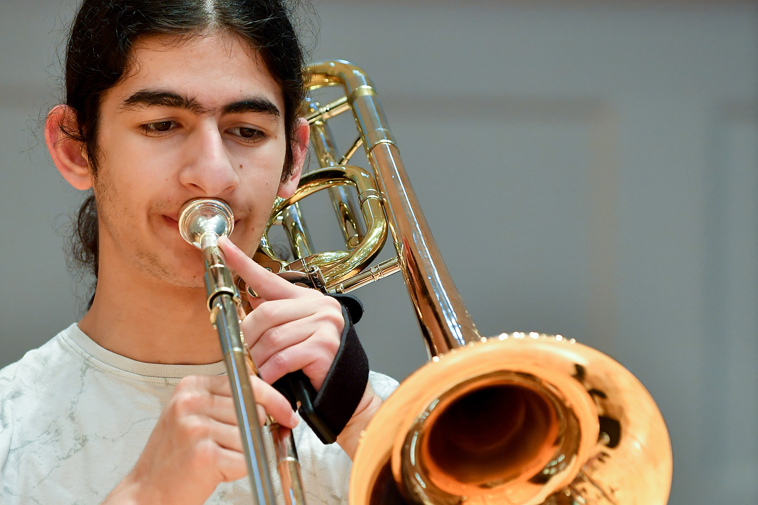 A brass student from the Junior Department performs on a trombone