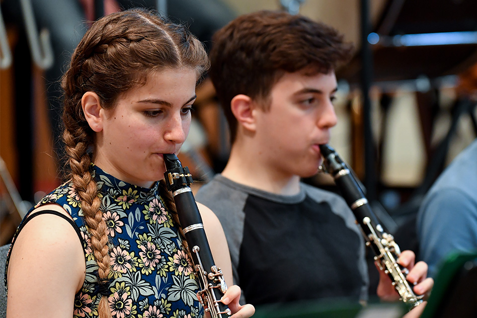 Two young people play the clarinet in an orchestra