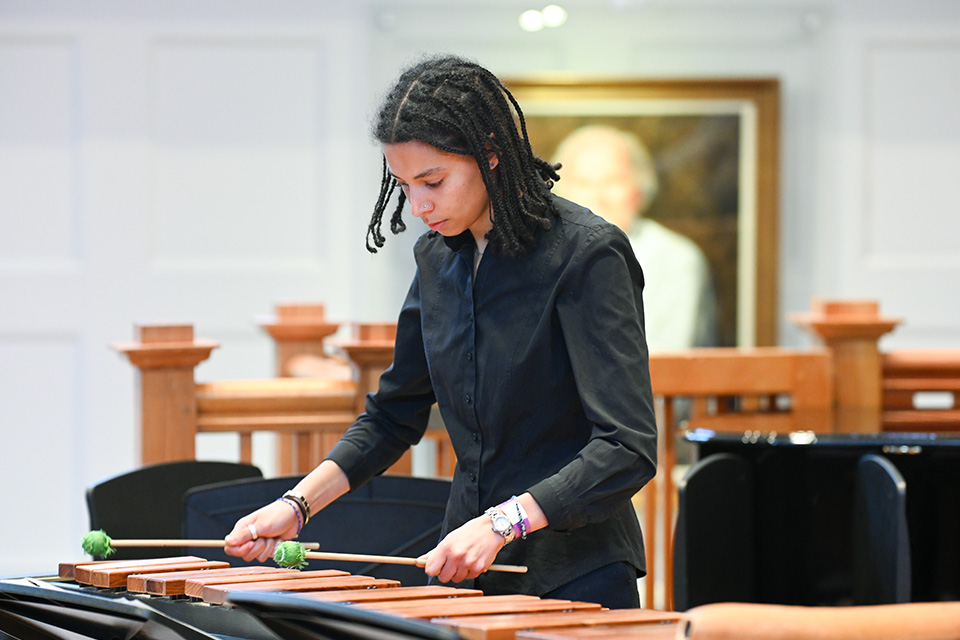 A young girl plays the marimba on stage