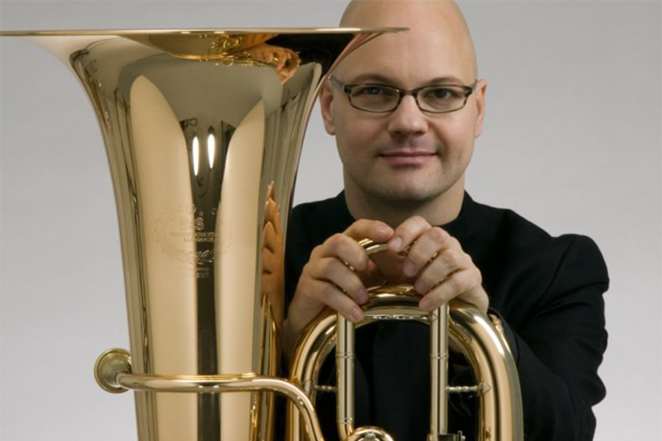 Jens Bjørn-Larsen wears black glasses and holds his tuba in front of him