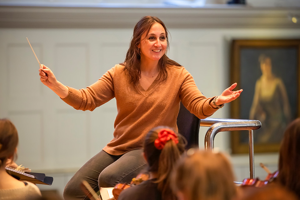 Joana Carneiro conducts an orchestra and smiles