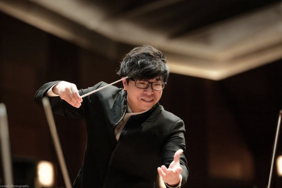 Kachun Wong wears black and conducts animatedly
