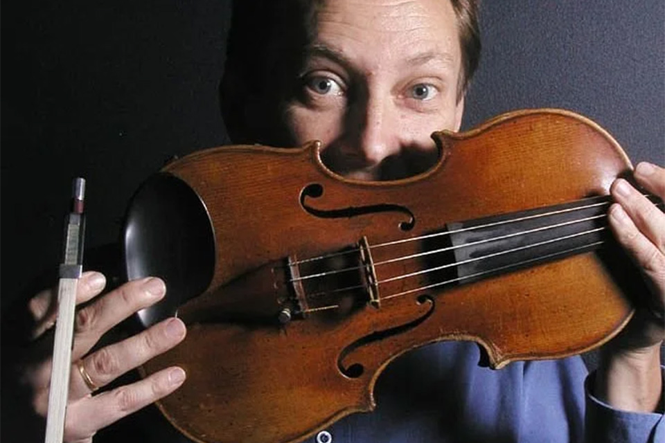 Mats Zetterqvist, wearing blue, holds his violin up to his face