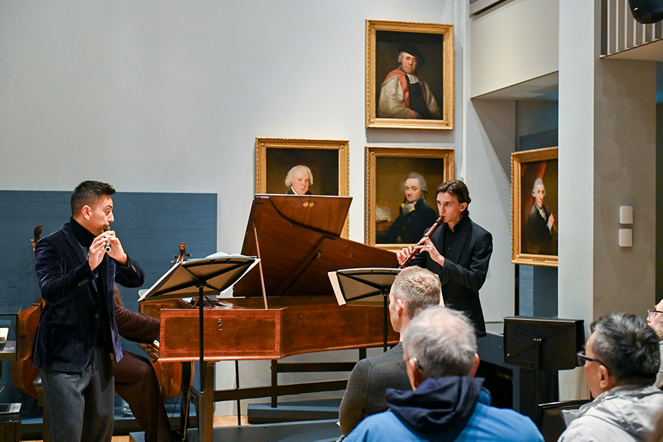 Two young men play recorders in a performance in the RCM Museum