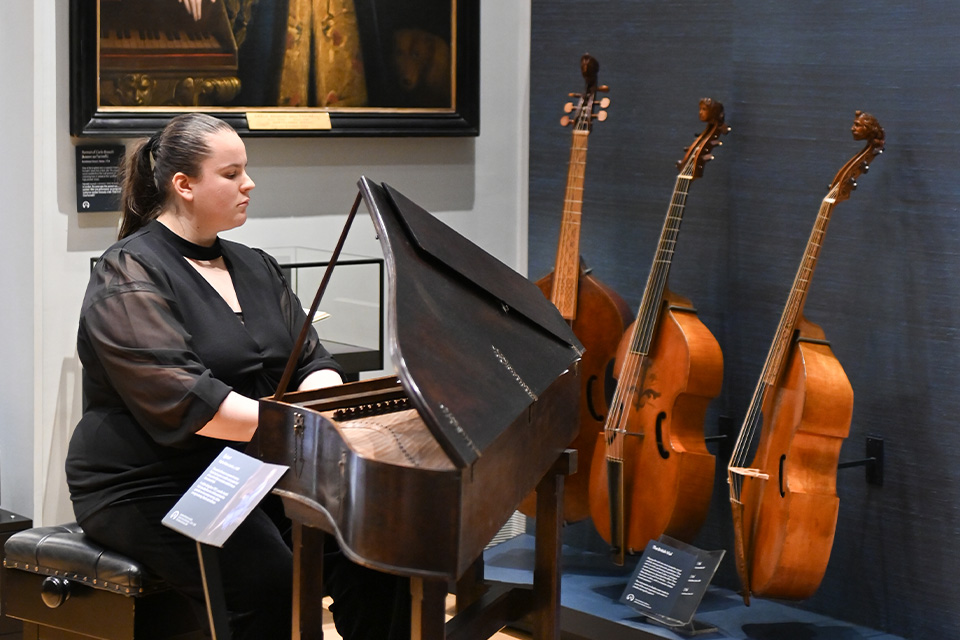 A woman plays the harpsichord in the RCM Museum