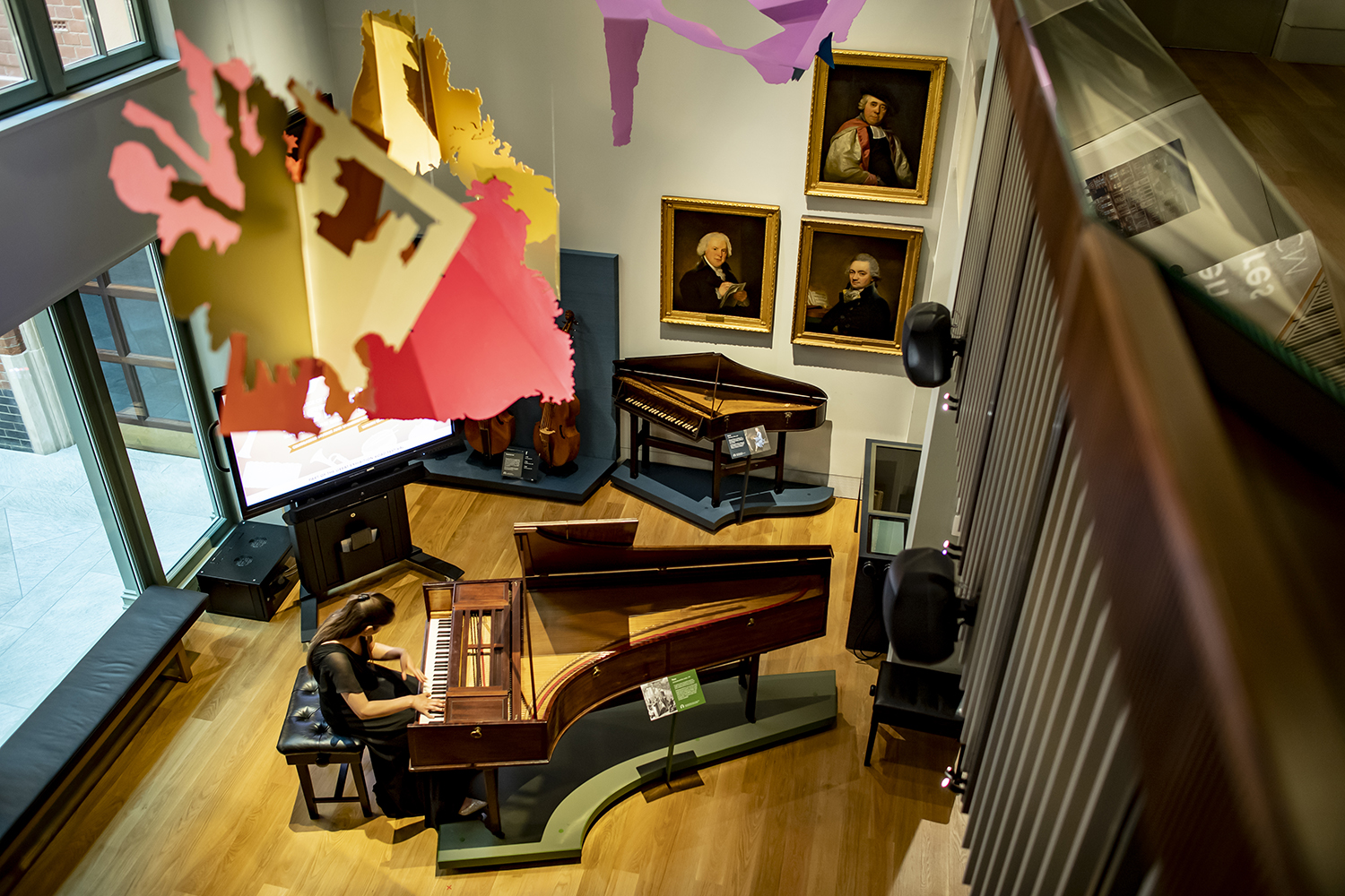A photograph taken from the balcony of a woman performing on a fortepiano in the RCM Museum