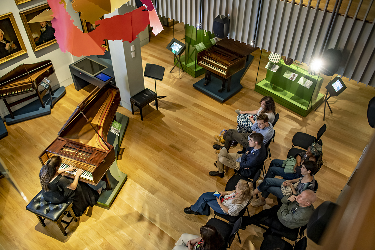 An audience watching a performer playing the piano in the RCM Museum