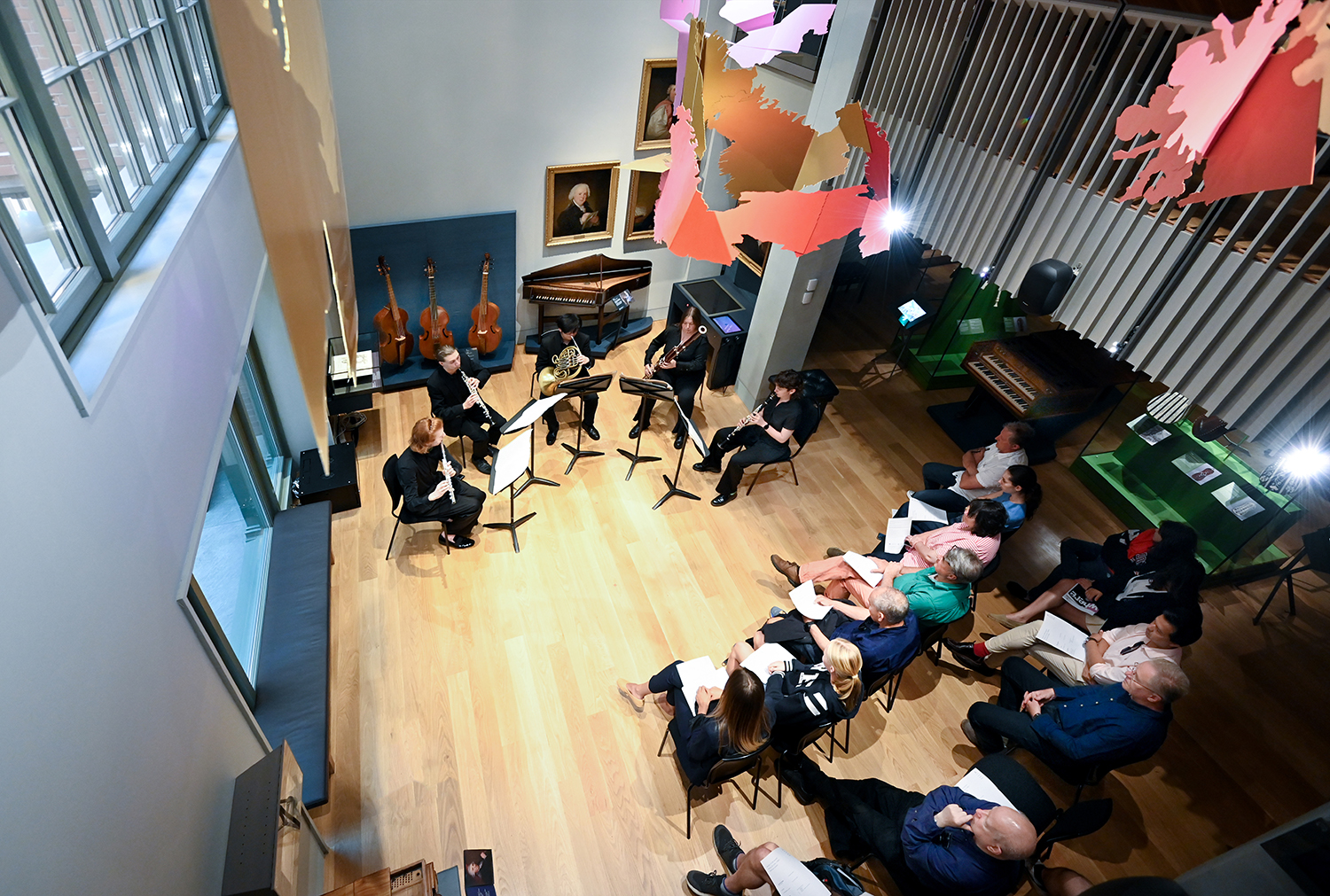 A photo taken from the balcony of a group of musicians performing in the RCM Museum to a full audience