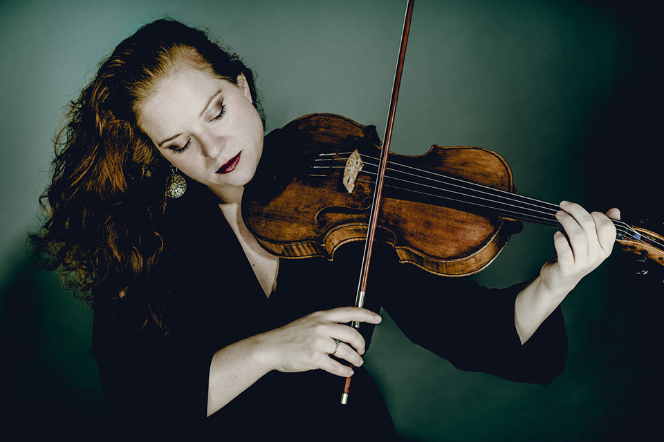 Nora Romanoff looks down at her viola as she plays it, her hair to the side over her other shoulder