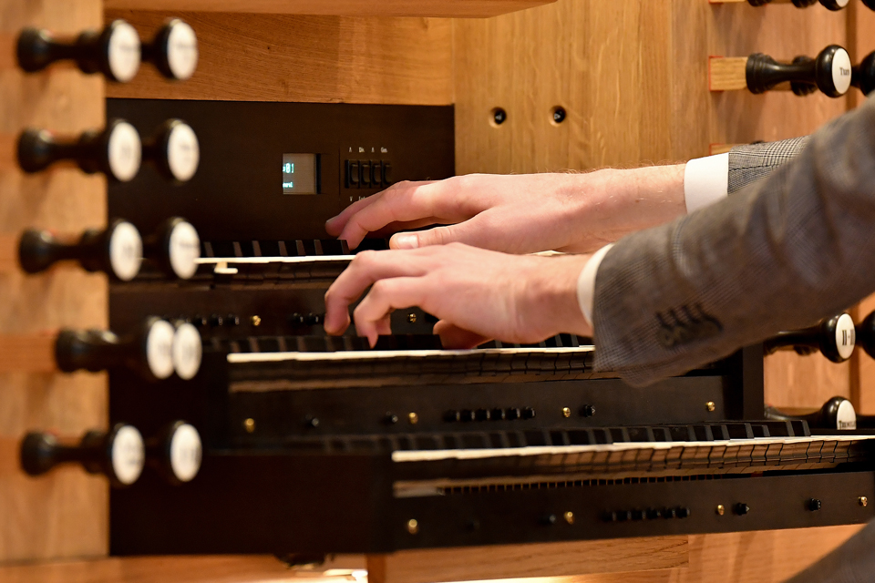 A close up photograph of someone's hand playing the organ