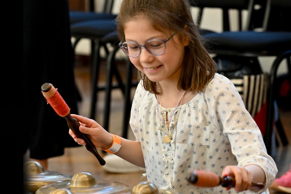 A young girls smiles as she holds two mallets