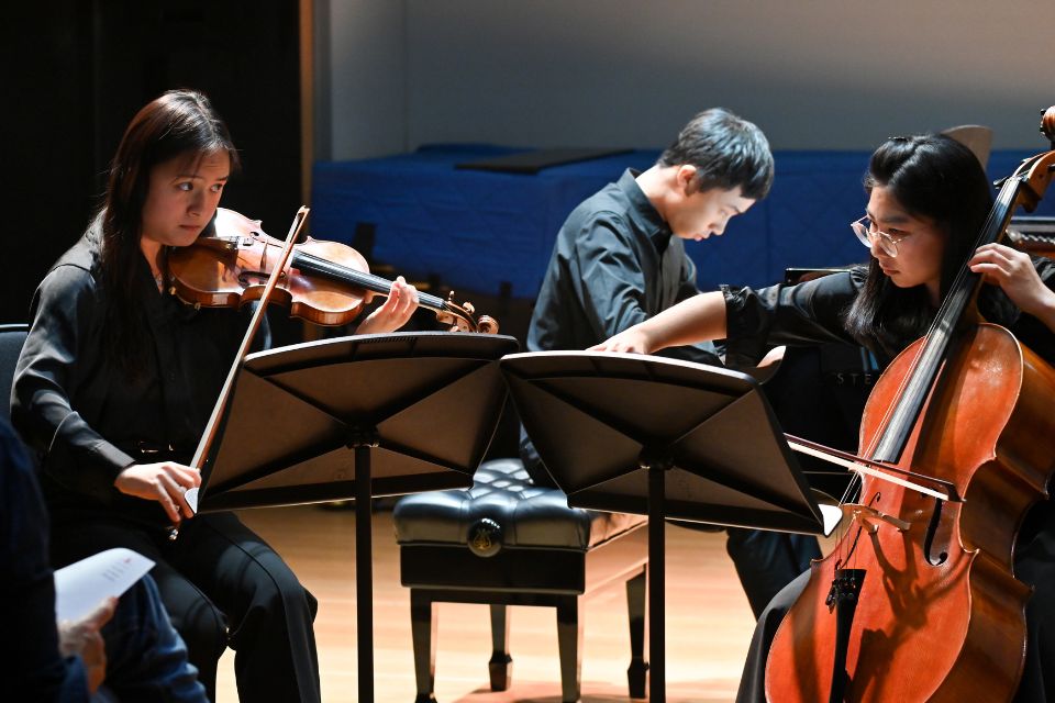 A pianist, violinist and cello perform on stage