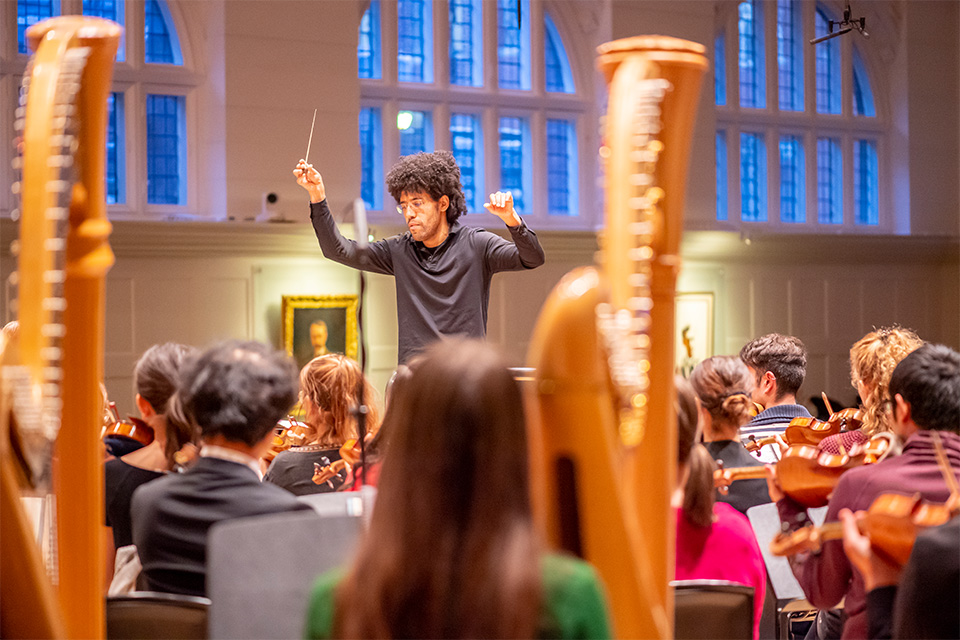 Rafael Payare wears a black shirt and conducts an orchestra