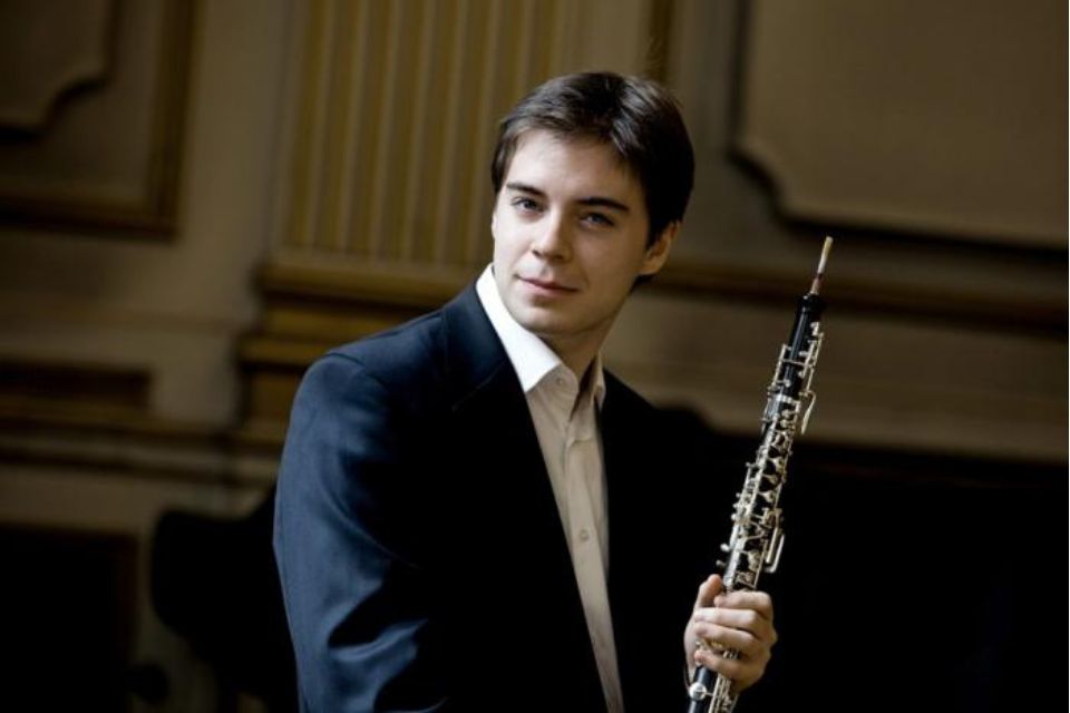 Ramón Ortega Quero wears a shirt and blazer and holds his oboe, looking to the side