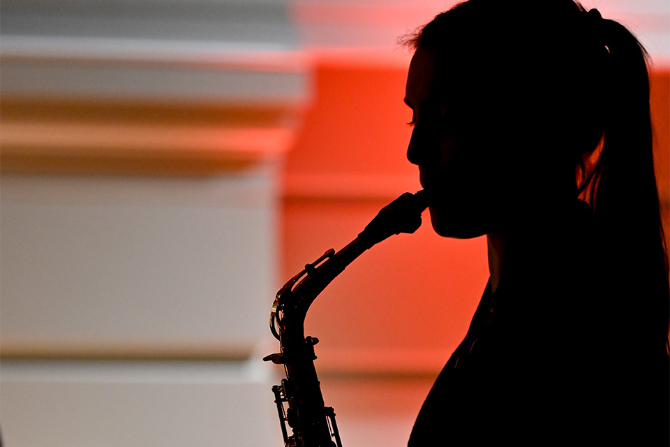 The silhouette of a student from the Junior Department playing the saxophone