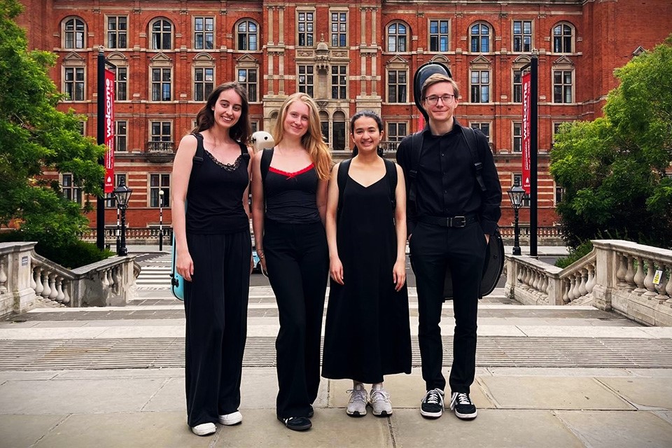 The Sonora Quartet stand in front of the Royal College of Music on a sunny day