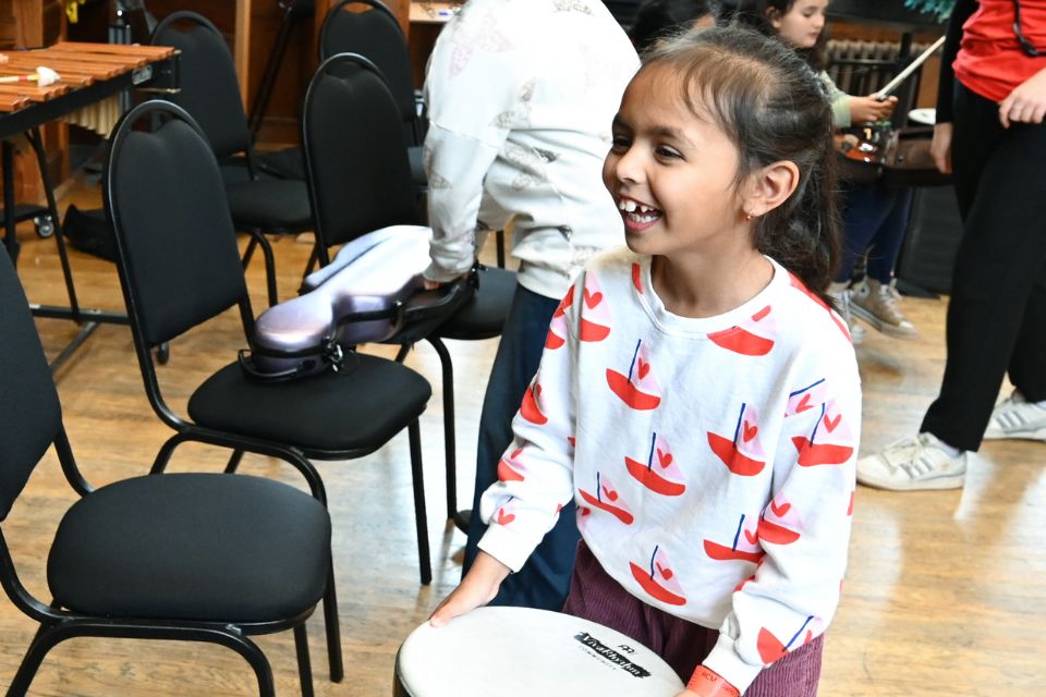 A young girl holds a drum and laughs