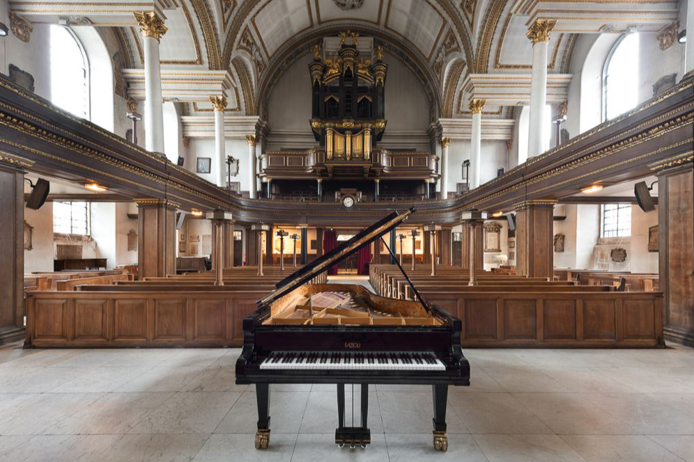 The interior of a church with a grand piano on the alter