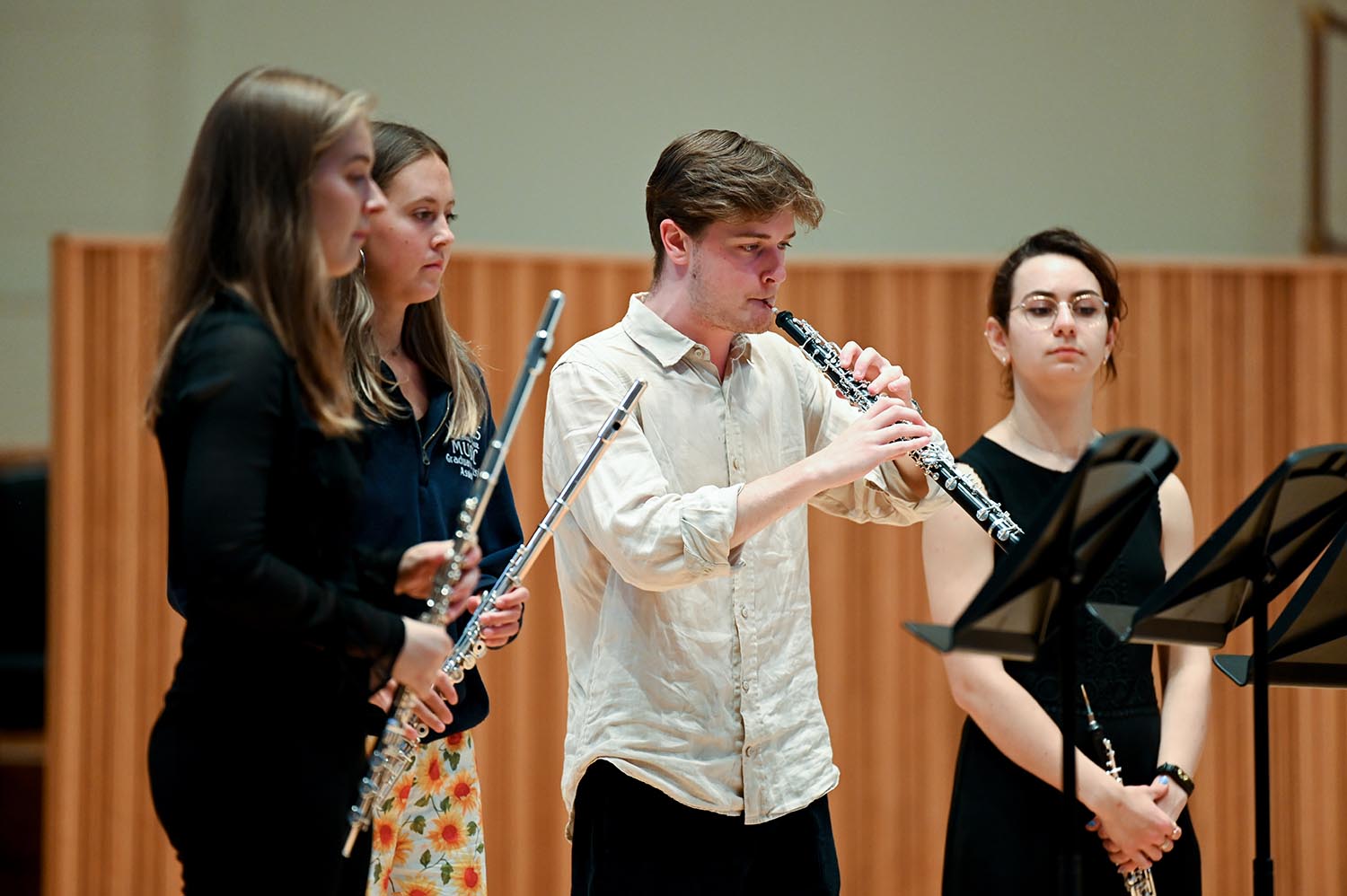 Four wind musicians perform on stage with the focus on a man playing an oboe